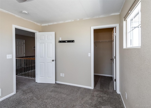 unfurnished bedroom with dark carpet, a walk in closet, and a closet