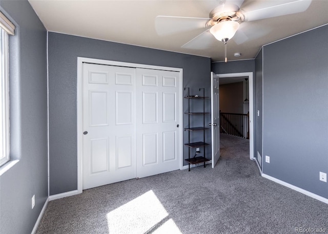 unfurnished bedroom with ceiling fan, a closet, and carpet flooring