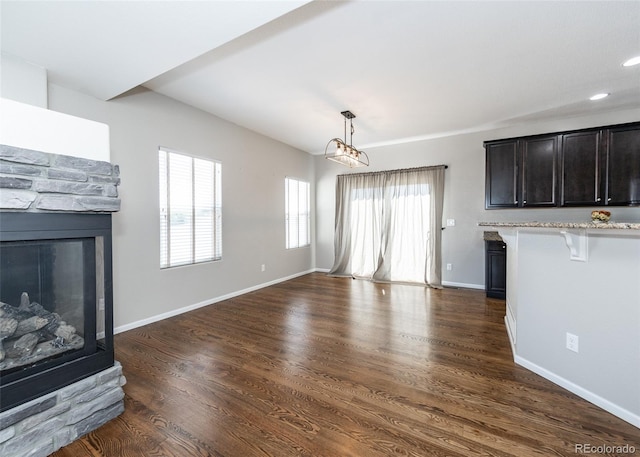 unfurnished living room featuring a fireplace, dark hardwood / wood-style flooring, and a notable chandelier