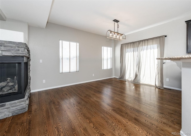 unfurnished living room featuring a fireplace, dark wood-type flooring, and a chandelier