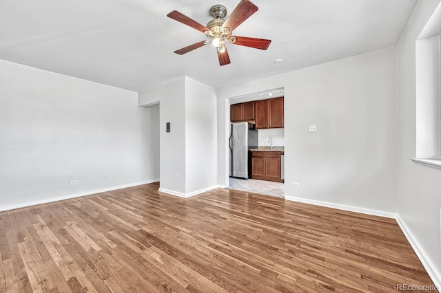 unfurnished living room featuring ceiling fan, sink, and light hardwood / wood-style floors