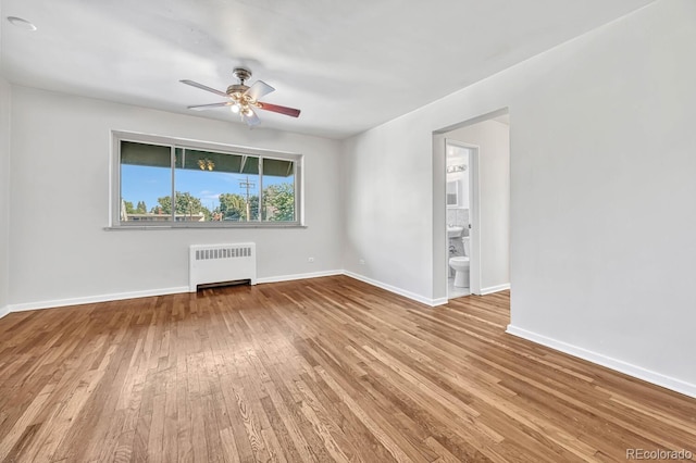 empty room featuring ceiling fan, radiator heating unit, and hardwood / wood-style flooring