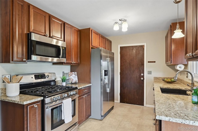 9306 Garrison Dr, Broomfield, CO 80021 - kitchen with appliances with stainless steel finishes, a sink, light stone counters, baseboards, and brown cabinets