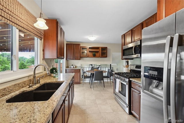 9306 Garrison Dr, Broomfield, CO 80021 - kitchen featuring stainless steel appliances, a sink, light stone counters, pendant lighting, and light tile patterned flooring
