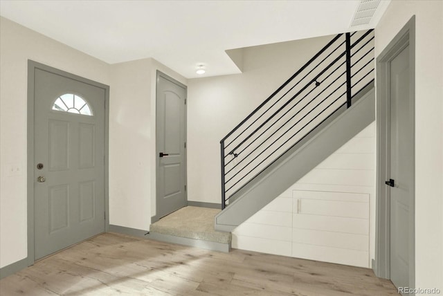 entrance foyer with light wood finished floors, stairway, visible vents, and baseboards