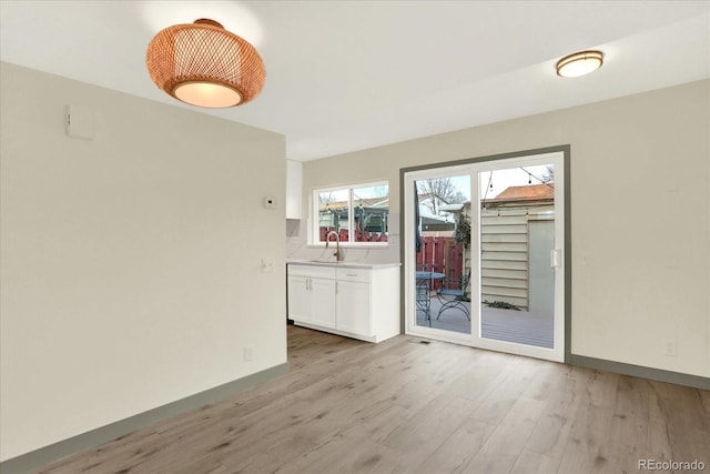 empty room featuring baseboards, a sink, and light wood finished floors