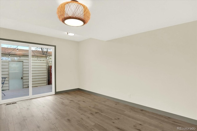 spare room with visible vents, baseboards, and wood finished floors