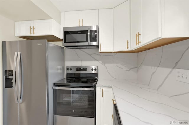 kitchen with stainless steel appliances, tasteful backsplash, white cabinetry, and light stone countertops