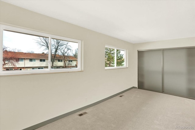 unfurnished bedroom featuring light carpet, a closet, visible vents, and baseboards