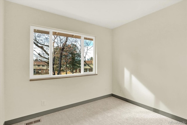 spare room with baseboards, visible vents, and light colored carpet