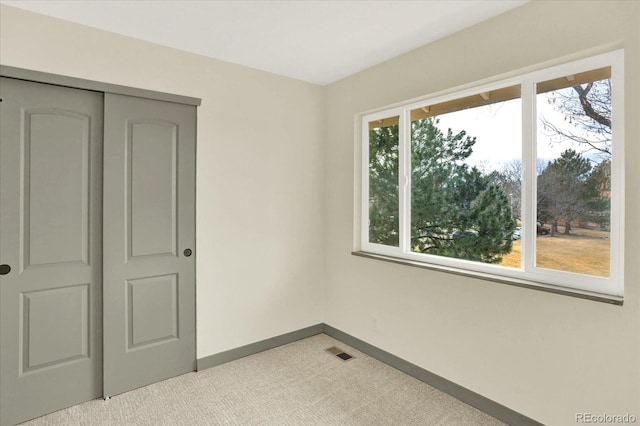 unfurnished bedroom featuring light carpet, baseboards, visible vents, and a closet