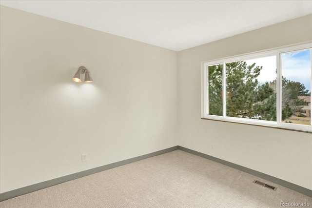 carpeted spare room featuring visible vents and baseboards