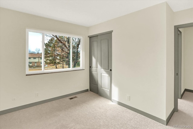 unfurnished bedroom featuring light carpet, baseboards, visible vents, and a closet