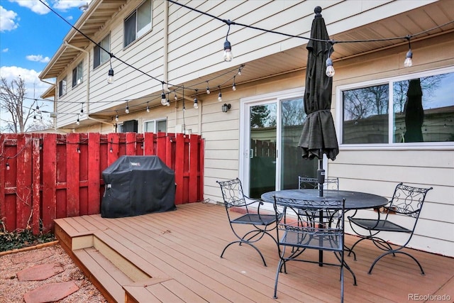 wooden deck featuring a grill, fence, and outdoor dining area