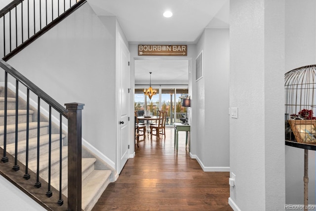 stairs featuring hardwood / wood-style floors and a notable chandelier