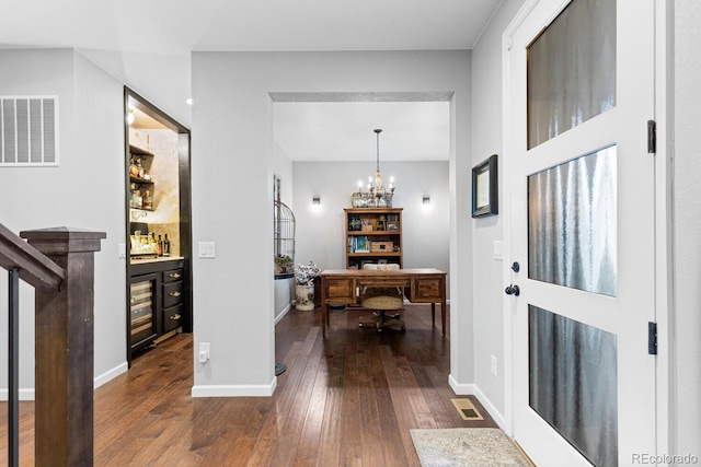 foyer entrance featuring wine cooler, dark hardwood / wood-style floors, and an inviting chandelier