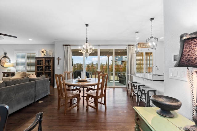 dining room featuring ceiling fan with notable chandelier, dark wood-type flooring, and sink