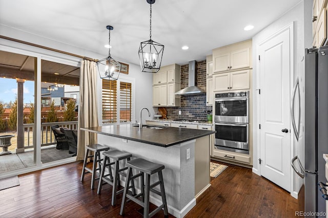 kitchen with dark hardwood / wood-style flooring, wall chimney range hood, sink, and stainless steel appliances