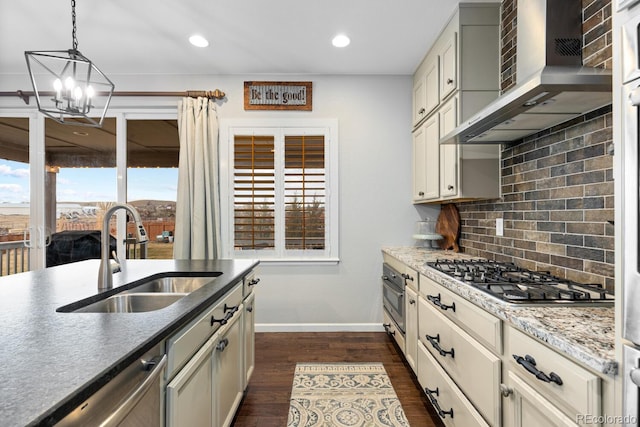 kitchen featuring sink, dark wood-type flooring, wall chimney range hood, decorative backsplash, and appliances with stainless steel finishes