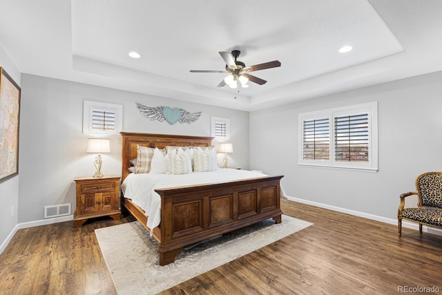 bedroom with a tray ceiling, ceiling fan, and dark hardwood / wood-style flooring