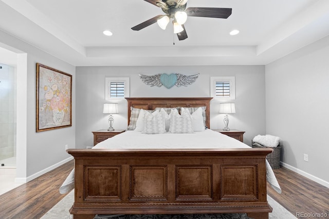 bedroom featuring a tray ceiling, ensuite bath, ceiling fan, and dark hardwood / wood-style floors