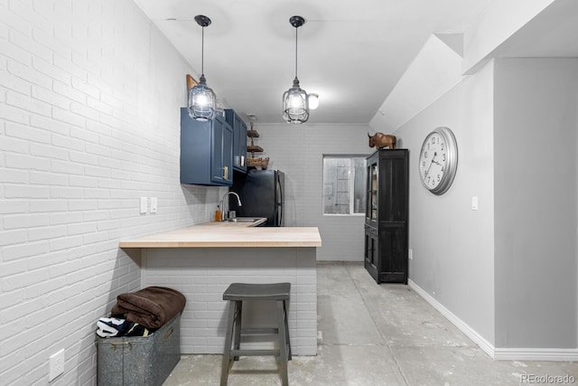 kitchen with kitchen peninsula, a kitchen bar, sink, blue cabinetry, and butcher block counters