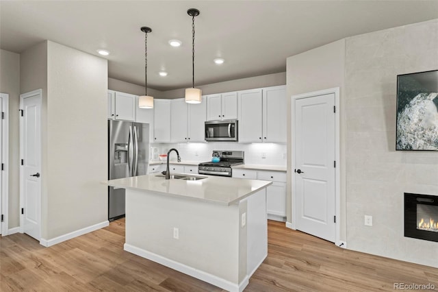 8387 Donati Ter Unit A, Littleton, CO 80129 - kitchen featuring stainless steel appliances, light wood-style floors, light countertops, white cabinetry, and an island with sink