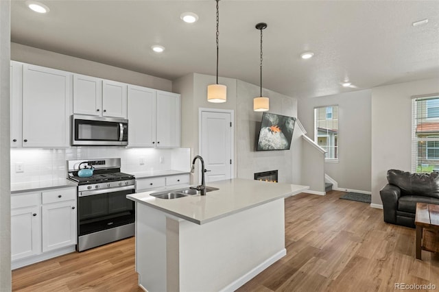 8387 Donati Ter Unit A, Littleton, CO 80129 - kitchen featuring stainless steel appliances, open floor plan, light wood-style flooring, tasteful backsplash, and white cabinetry