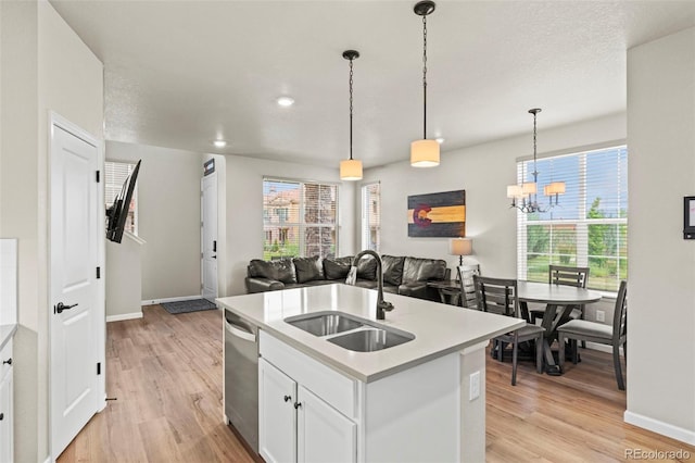 8387 Donati Ter Unit A, Littleton, CO 80129 - kitchen with stainless steel dishwasher, a chandelier, open floor plan, light wood-type flooring, and light countertops
