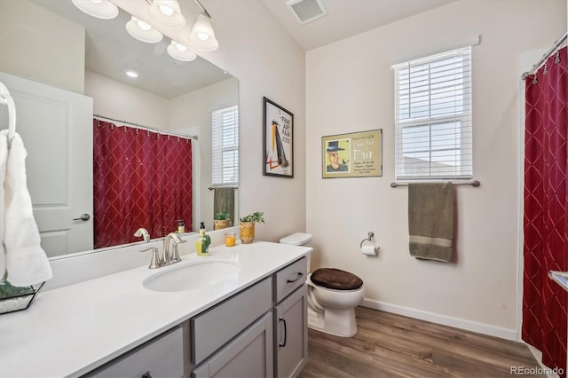 bathroom featuring a wealth of natural light, vanity, wood-type flooring, and toilet