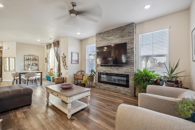 living room featuring a fireplace, wood-type flooring, and ceiling fan