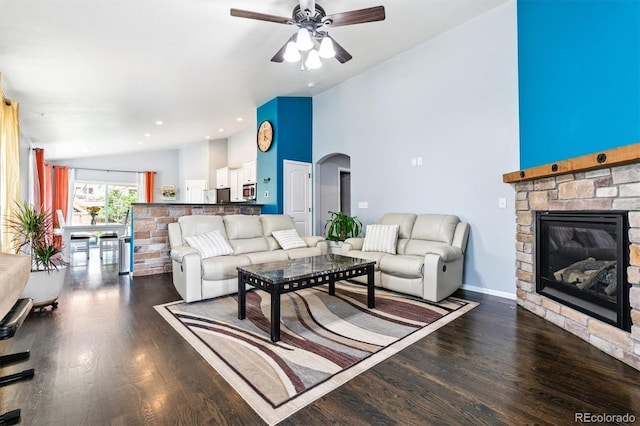 10288 Olathe Way, Commerce City, CO 80022 - living area with ceiling fan, arched walkways, dark wood-style flooring, a stone fireplace, and high vaulted ceiling