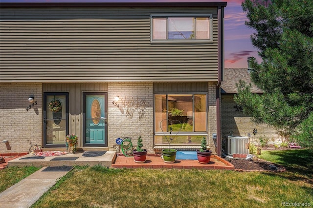 4541 W Ponds Cir, Littleton, CO 80123 - exterior entry at dusk featuring brick siding and a yard