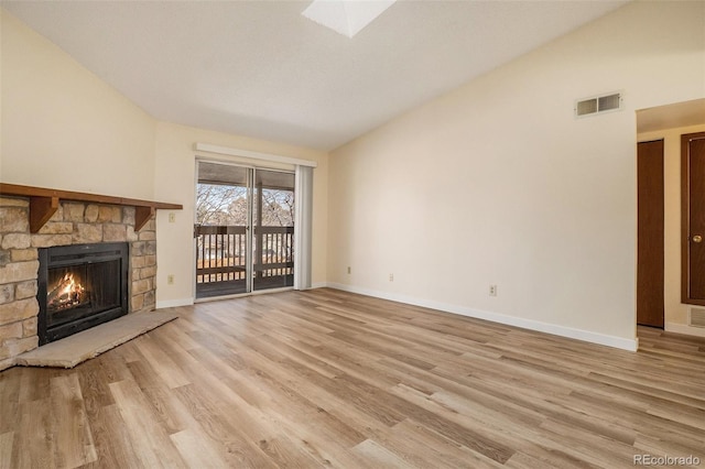 unfurnished living room featuring visible vents, baseboards, vaulted ceiling, light wood-style flooring, and a fireplace