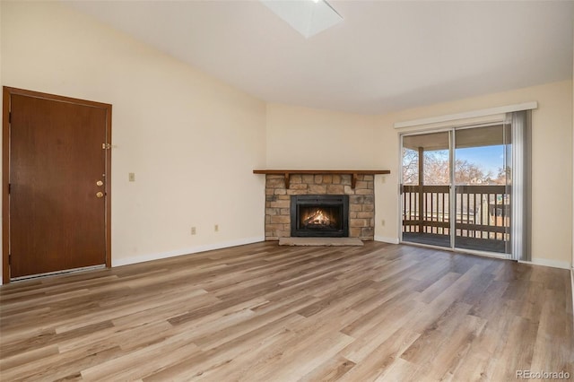 unfurnished living room with baseboards, a stone fireplace, and wood finished floors