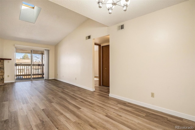 unfurnished living room with visible vents, baseboards, a chandelier, lofted ceiling, and wood finished floors