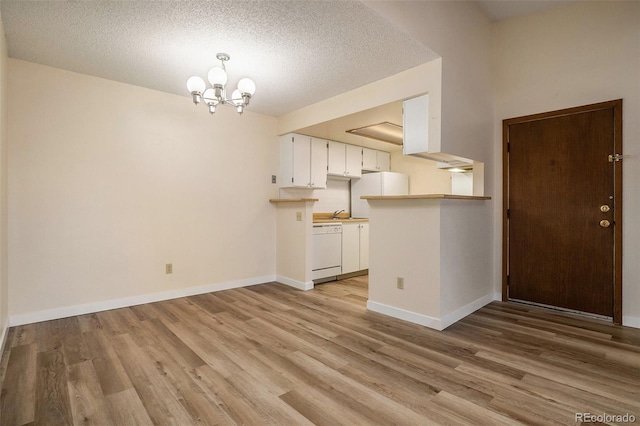 kitchen featuring light wood finished floors, white cabinetry, dishwasher, and an inviting chandelier