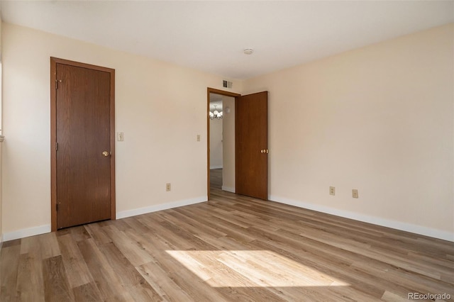 unfurnished room featuring light wood finished floors, visible vents, and baseboards