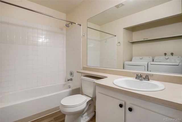 bathroom with toilet, bathtub / shower combination, wood finished floors, vanity, and separate washer and dryer