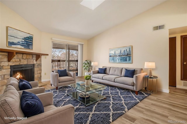 living area featuring visible vents, wood finished floors, baseboards, a fireplace, and lofted ceiling