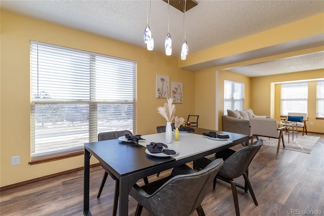 dining space with wood-type flooring and a textured ceiling