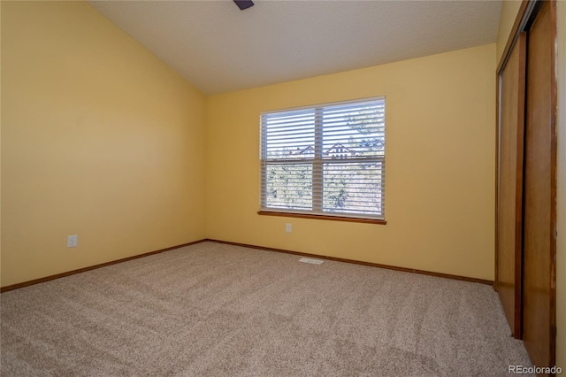 unfurnished bedroom featuring lofted ceiling, light carpet, and a closet