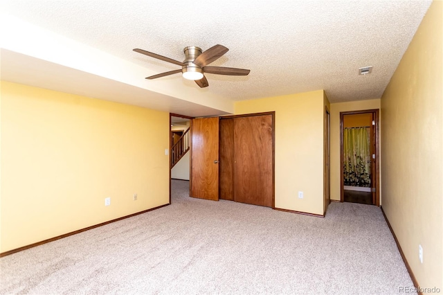 unfurnished bedroom with light carpet, a textured ceiling, a closet, and ceiling fan