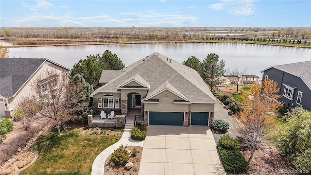 view of front of home featuring roof with shingles, a water view, an attached garage, and driveway