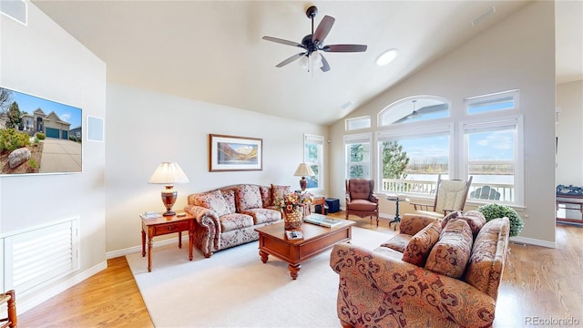 living area featuring a ceiling fan, baseboards, high vaulted ceiling, and light wood-style floors