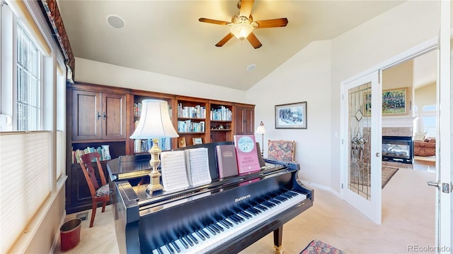 sitting room with light carpet, baseboards, a ceiling fan, a multi sided fireplace, and vaulted ceiling