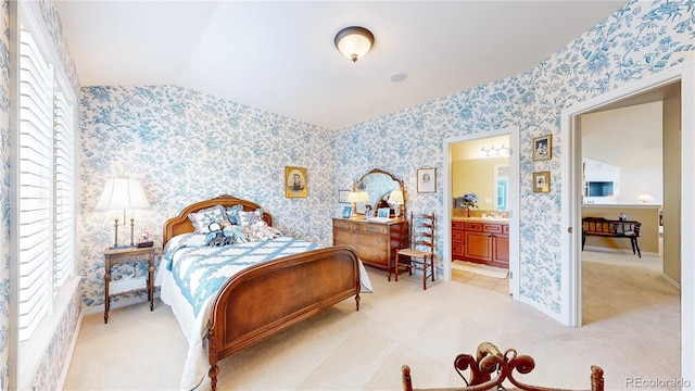 bedroom with light carpet, baseboards, wallpapered walls, connected bathroom, and vaulted ceiling