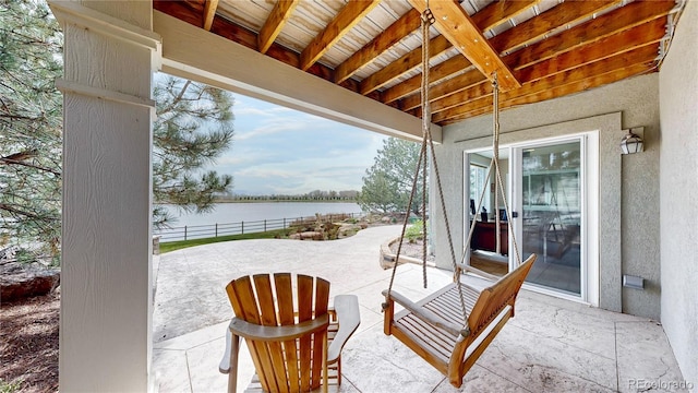view of patio featuring a water view and fence