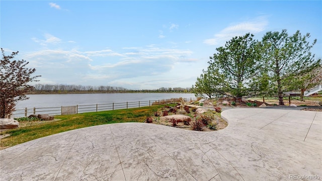 view of patio with fence and a water view