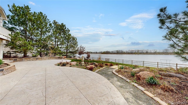 view of patio with a water view and fence
